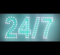 Bright LED sign displaying “24/7” with white and green lights indicating кругл-the-clock availability